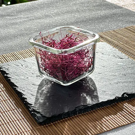 Ein Schälchen Amaranth Microgreens in der Sonne auf einer Schieferplatte