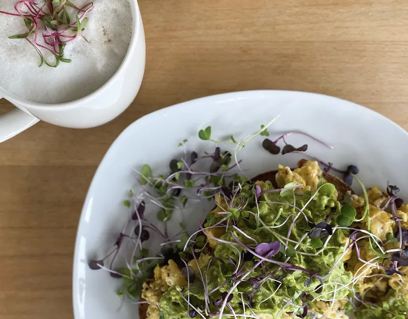 Rührei Frühstück mit verschiedenen Microgreens garniert und einem Kaffee